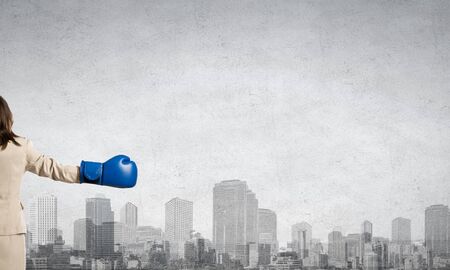 Young businesswoman in blue boxing gloves competition readyの写真素材