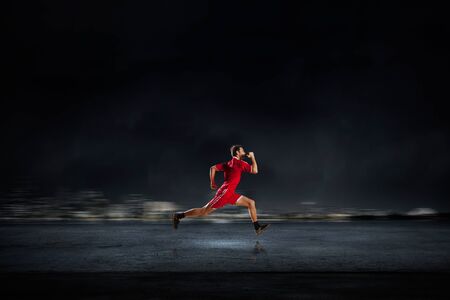 Running man in red sport wear on dark backgroundの写真素材