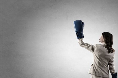 Young businesswoman in blue boxing gloves competition readyの写真素材