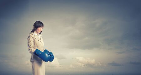 Young confident businesswoman wearing blue boxing glovesの写真素材