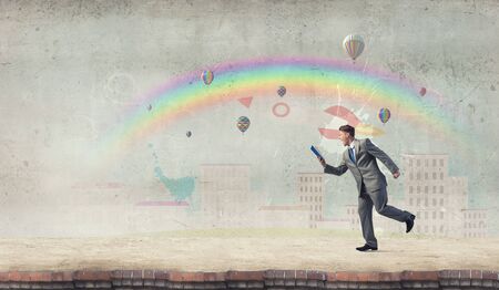 Young businessman running with book in handの写真素材