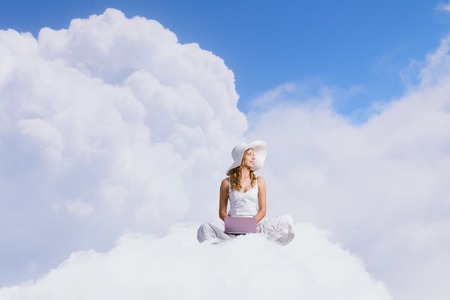 Young lady sitting on cloud with laptop on kneesの写真素材