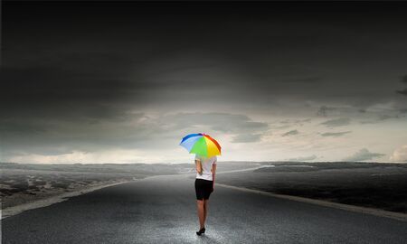 Back view of businesswoman in suit with colorful umbrellaの写真素材