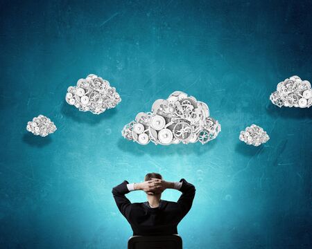 Thoughtful businessman with gear mechanisms above his headの写真素材