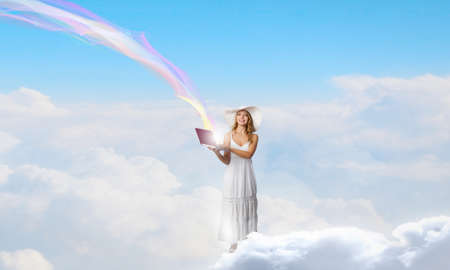 Young lady standing on cloud and using laptopの写真素材