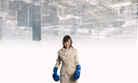 Young businesswoman in blue boxing gloves competition readyの写真素材