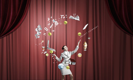 Young businesswoman in cap on stage juggling with iconsの写真素材