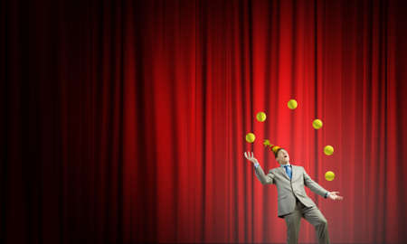 Young businessman in cap on stage juggling with ballsの写真素材