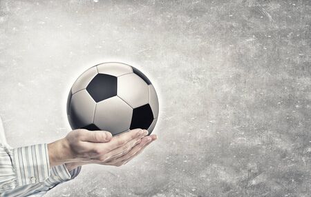 Close up of businessman holding soccer ball in handの写真素材