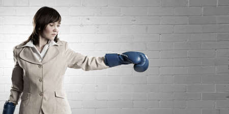 Young businesswoman in blue boxing gloves competition readyの写真素材