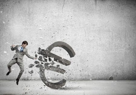 Businessman breaking stone euro symbol with karate punchの写真素材