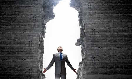 Businessman with hands spread apart standing in light coming from aboveの写真素材