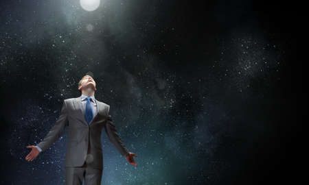 Businessman with hands spread apart on dark backgroundの写真素材