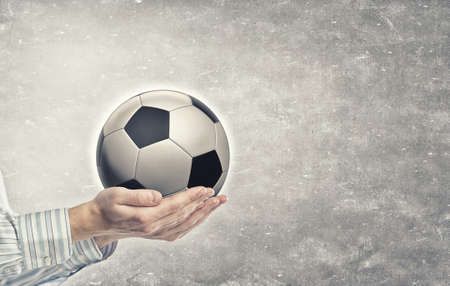 Close up of businessman holding soccer ball in handの写真素材