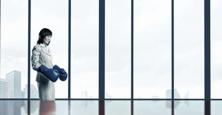 Young businesswoman in blue boxing gloves competition readyの写真素材