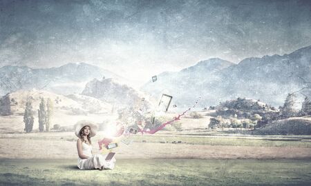 Young lady sitting on floor with laptop on kneesの写真素材