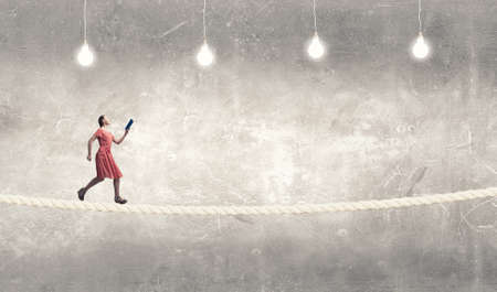 Young woman in red dress running with book in handの写真素材