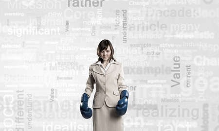 Young businesswoman in blue boxing gloves competition readyの写真素材
