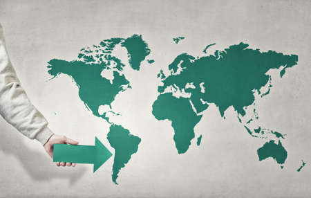 Close up of hand pointing with arrow at world mapの写真素材