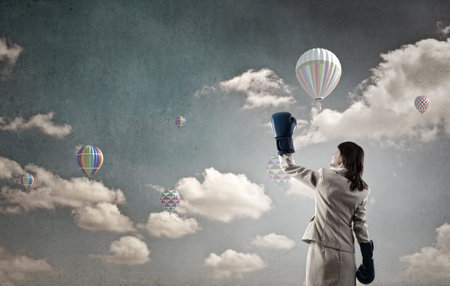 Young businesswoman in blue boxing gloves competition readyの写真素材