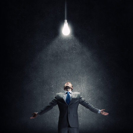 Businessman with hands spread apart and light bulb above