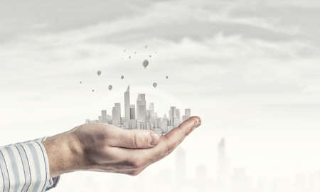 Close up of hands holding image of modern cityscapeの写真素材