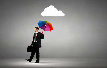 Businessman standing with umbrella under cloud conceptの写真素材