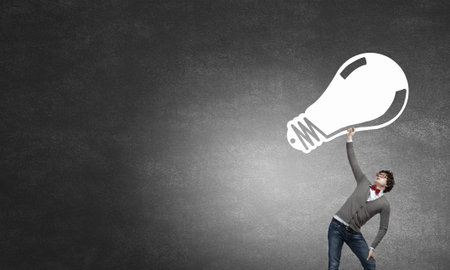 Young businessman holding in hands big light bulbの写真素材