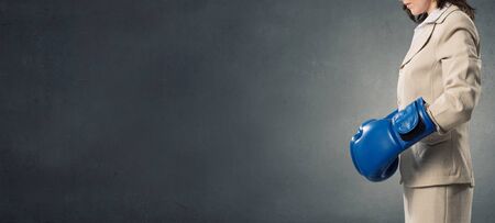 Young businesswoman in blue boxing gloves competition readyの写真素材