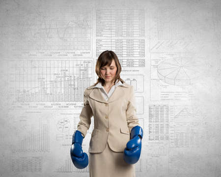 Young businesswoman in blue boxing gloves competition readyの写真素材