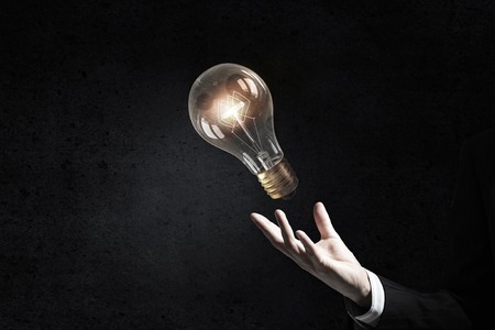 Businessman presenting glass glowing light bulb in his handの写真素材