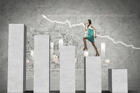 Young businesswoman stepping up on chart barの写真素材