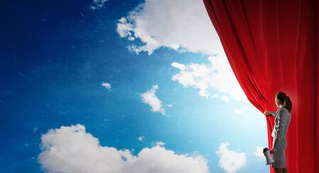 Young businesswoman opening stage curtain to another realityの写真素材