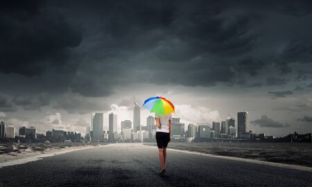 Back view of businesswoman in suit with colorful umbrellaの写真素材