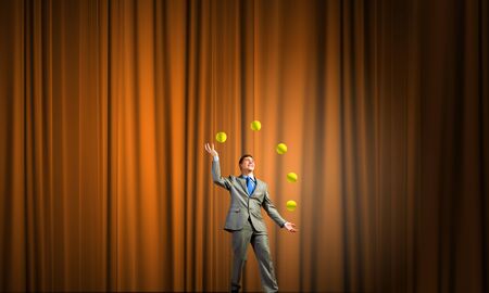 Young businessman in cap on stage juggling with ballsの写真素材