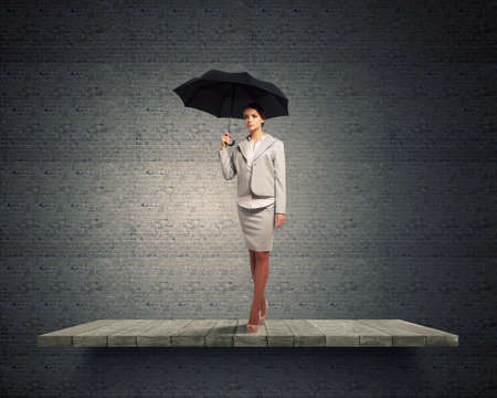 Young pretty businesswoman in suit with black umbrellaの写真素材