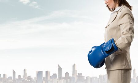 Young businesswoman in blue boxing gloves competition readyの写真素材