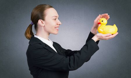 Young businesswoman holding yellow rubber duck toy in palmの写真素材