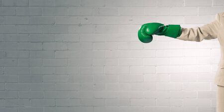 Young businesswoman in green boxing gloves competition readyの写真素材