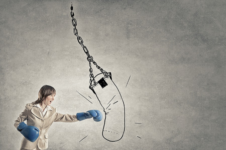 Young confident businesswoman wearing blue boxing glovesの写真素材