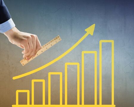Close up of hand measuring growing graph with rulerの写真素材
