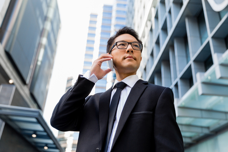 Businessman in city holding his mobileの写真素材