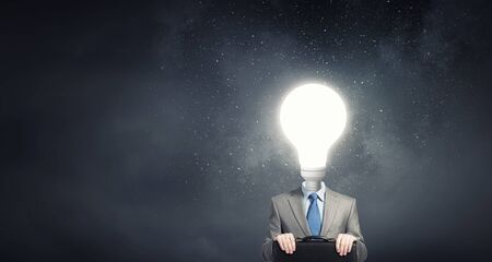 Businessman in suit with light bulb instead of headの写真素材