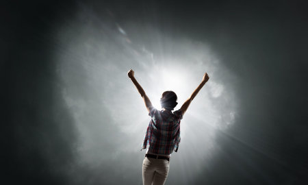 Rear view of woman with hands up facing success