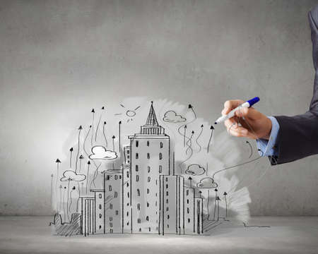Close up of businessman hand drawing sketches of buildingsの写真素材