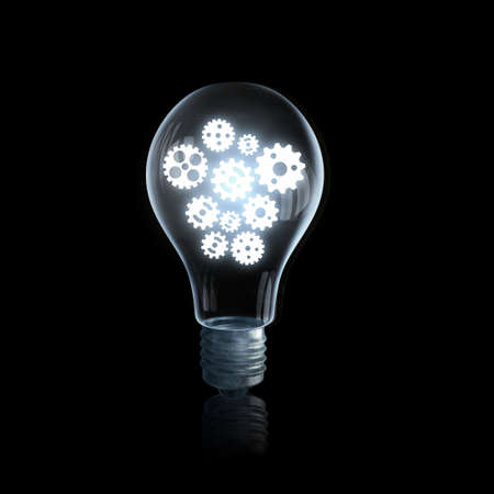 Glass light bulb with gears inside on black backgroundの写真素材