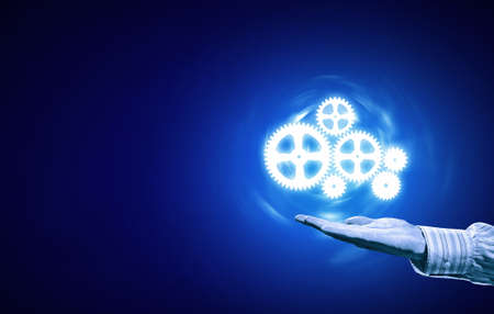 Businessperson hand holding gears and cogwheels in palmの写真素材