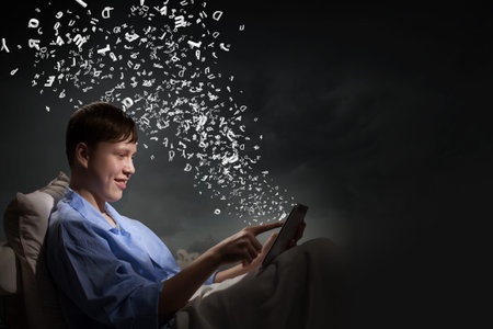 Young teenager guy in bed using tablet pcの写真素材