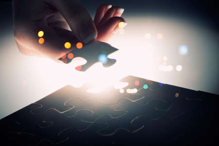 Hand connecting missing jigsaw glowing puzzle pieceの写真素材