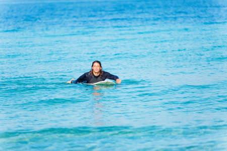 A young surfer with his board on the beachの写真素材
